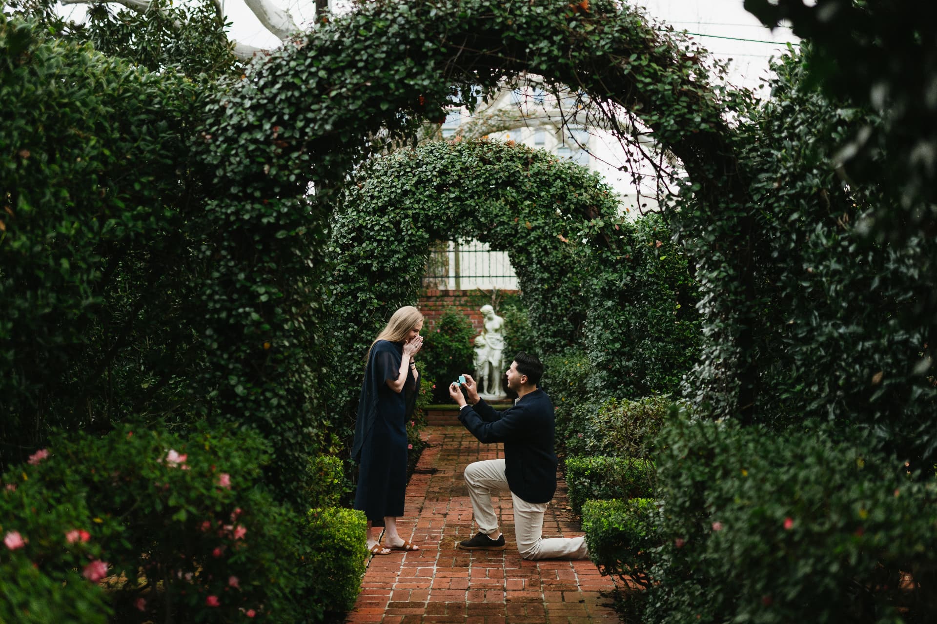Wasi and Hope at the moment of the proposal, framed by the garden arches and brick pathway