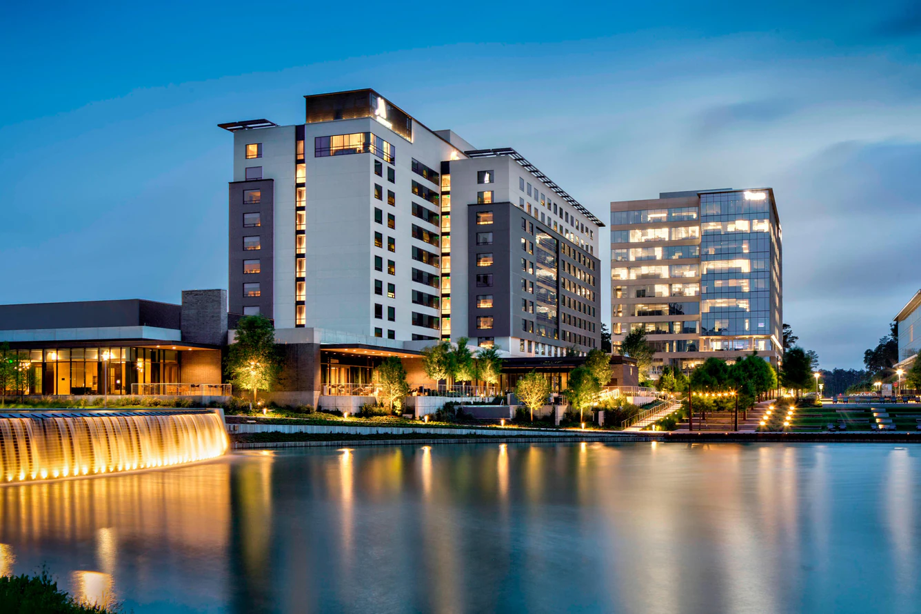 The Houston CityPlace Marriott reflected in the lake at dusk, with the illuminated water wall